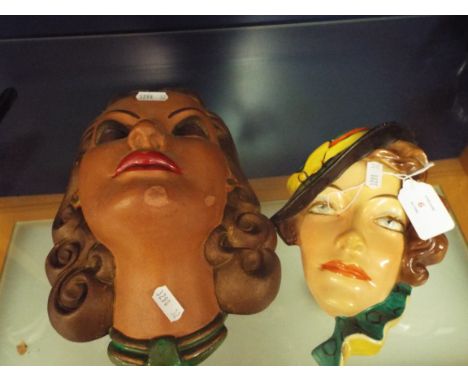 A Czechoslovakian ceramic Art Deco wall mask of a lady in green hat together with another example     left hand mask has over