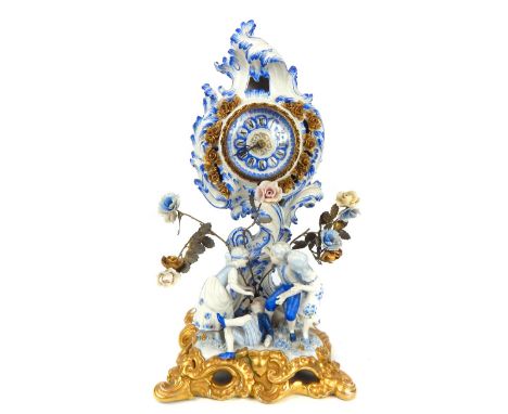 A 19th / 20th century French blue and white porcelain figurative mantle clock, of roccoco form, the porcelain chapter ring wi