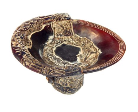 A Chinese carved horn libation cup, in the typical form, carved with a village, with 'S' scroll handle, the carved bowl with 