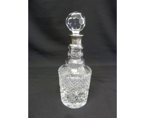 A cut glass decanter with drop stopper and silver collar