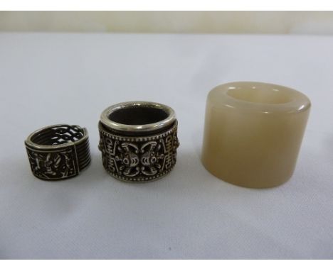 Two Oriental white metal archery rings and a jade archery ring