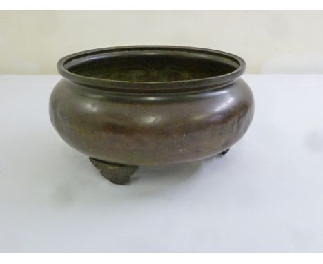 A Chinese bronze incense burner, circular on three bracket feet, marks to the base