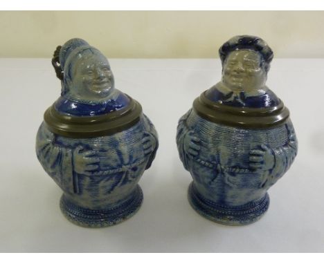 A pair of ceramic steins with pewter fittings in the form of monks