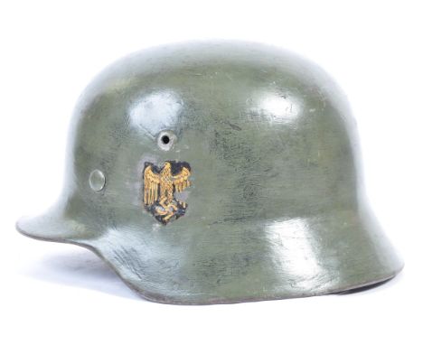 A WWII Second World War German Nazi Third Reich M35 steel combat helmet with rolled edge in green with tricolour and army eag
