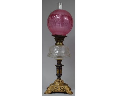 A Late Victorian Cast Iron Based Oil Lamp with Glass Reservoir and Acid Etched Cranberry Shade, Total Height 65cm 