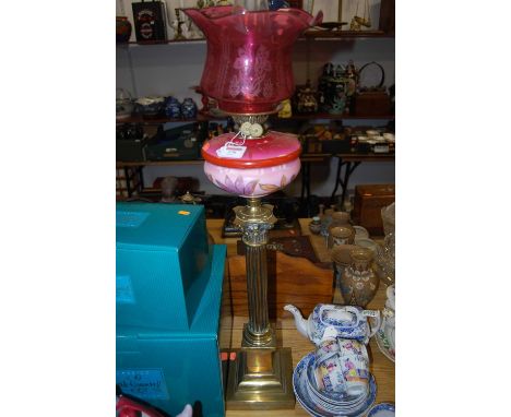 A Victorian pedestal oil lamp, having a cranberry tinted etched glass shade above a pink glass font with floral decoration, r