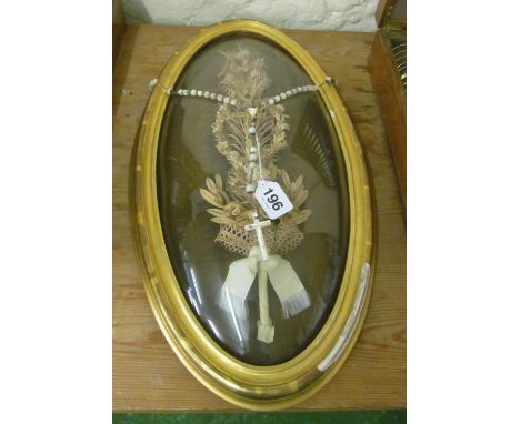 A Victorian cutwork cross surrounded by flowers in gilt frame with domed glass and a mother of pearl rosary