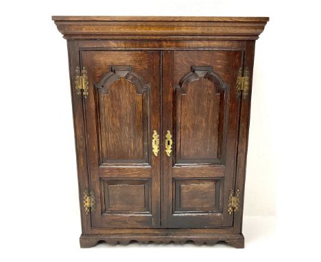 20th century oak spice cupboard, two twin fielded panel doors enclosing pigeon holes and series of shelves, on shaped apron a