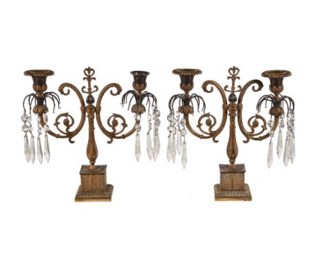  A pair of Regency gilt bronze twin light lustre candelabra,   circa 1815, the urn sockets hung around with faceted glass pen