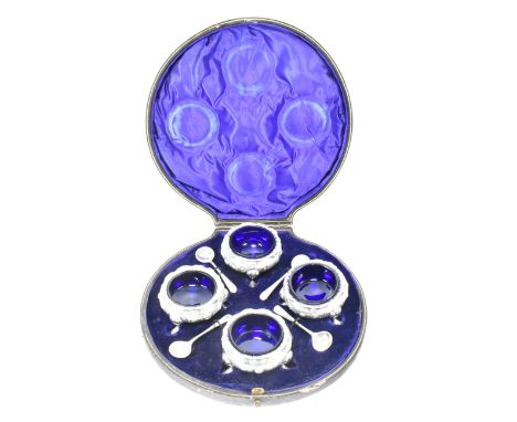 An early 20th century cased hallmarked silver salt set. The set to include four silver salts with blue glass liners and four 