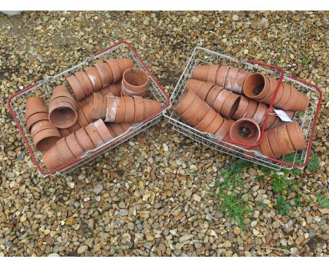 A quantity of vintage terracotta plant pots, each 9cm high, in two vintage plastic coated metal baskets/trugs, over 100 pots 