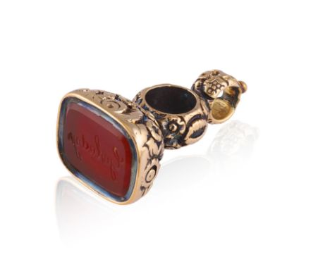 A FOB SEAL PENDANT Inset with a carnelian intaglio spelling out ‘Gwladys’ for ‘Saint Gladys’, to a mount with scrolled foliat