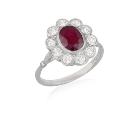 A RUBY AND DIAMOND RINGOf cluster design, set with an oval-shaped ruby weighing approximately 1.6cts, within a surround of br