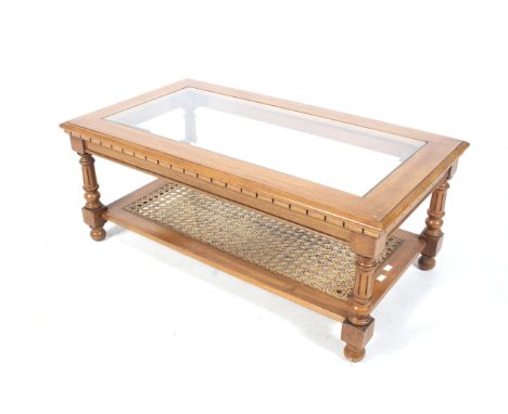 A vintage glass top coffee table. With a lower wicker work shelf, fluted column supports. L101cm x D56cm x H42cm