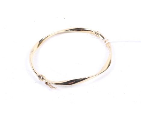 A modern hinged bangle stamped '375'. In the form of a hollow twist with an applied panel stamped 375 3.3g in a goldsmiths bo