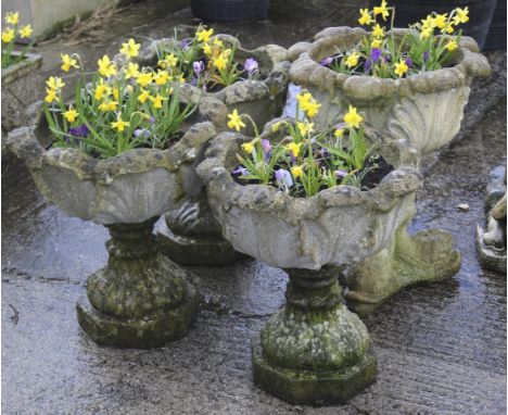 Four reconstituted stone garden urns. Comprising a set of three on octagonal bases, H52cm and a single one on a tripod base, 