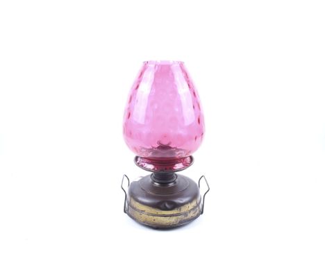 A Victorian brass oil lamp. With twin handles to the base, a tapered ruby glass shade and clear funnel, H52cm