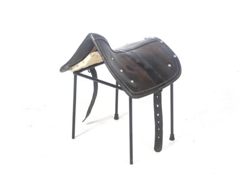 A vintage leather saddle stool. In the form of an antique horse or mule tip/cart harness saddle, supported on a black painted