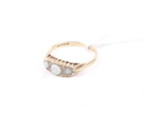 A vintage 9ct gold, opal and diamond dress ring. The three graduated oval white opals spaced by pairs of small eight cut diam