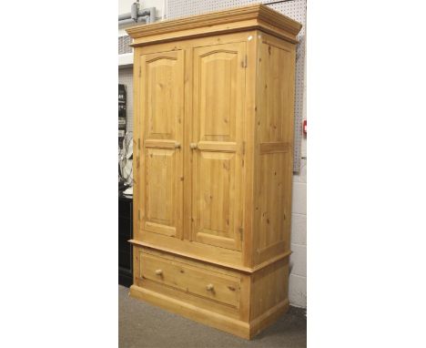 A contemporary two door pine wardrobe. Opening to reveal hanging area, raised over a single long drawer raised on a plinth ba