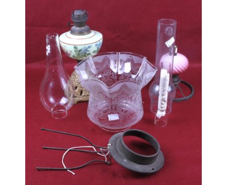 A selection of oil lamp components. Including a glass shade with floral decoration, a pink glass reservoir with ribbing, a ca
