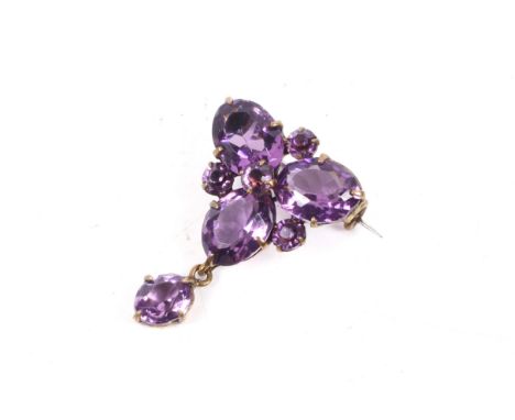 An early 20th century gold-plated and oval amethyst-coloured paste brooch. Of triangular outline with a single stone drop, L3