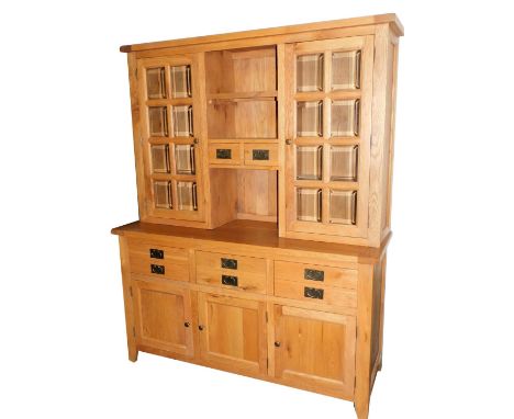 A light oak dresser, the top with two doors, each with bevelled panelled glass flanking two drawers and a shelf, the base wit