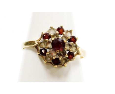 A 9ct gold dress ring, formed as a cluster set with layers of garnets and czs, on a raised basket, ring size O, 2.2g all in. 