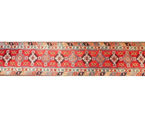A Turkish runner, with a design of eleven alternating medallions, in blue on a red ground with two wide borders, 504cm x 90cm