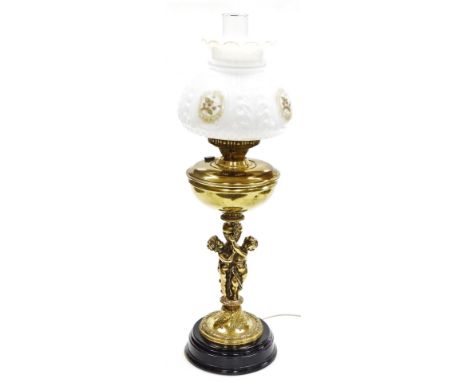 A brass oil lamp type electric table lamp, cast with a figural support, with clear glass chimney and moulded white glass shad