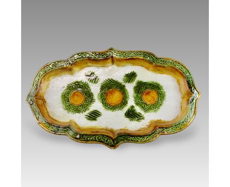 of oblong shape with shallow sides rising to an everted barbed rim, the interior impressed with three flowers in amber and gr