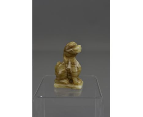 A Chinese carved celadon jade figure of a seated dog. 8cm tall