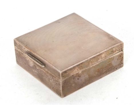 A hallmarked silver cigarette box of square form with engine turned decorated lid, plain polished sides with a wood interior,