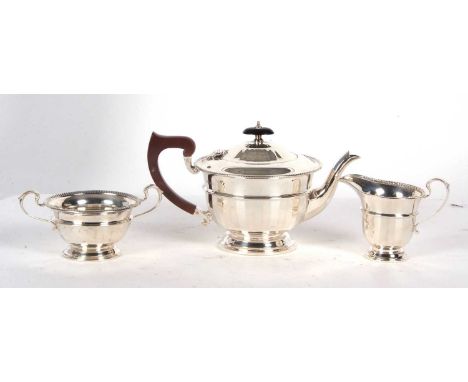 An Art Deco three piece silver tea service comprising teapot, cream jug and twin handled sugar bowl, of circular form with pa