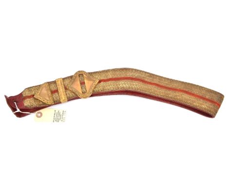 An officer's gilt lace shoulder belt of the Army Ordnance Corps, scarlet central stripe and leather backing, gilt buckle, tip