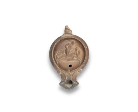  A Roman terracotta oil lamp with erotic scene Circa 1st Century B.C.-1st Century A.D.Red-slipped, with a volute nozzle and r