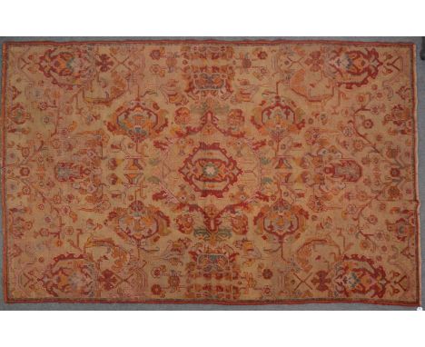 19th century Persian carpet, large central motif surrounded by similar flowerheads and flowering vines, in tones of red and o