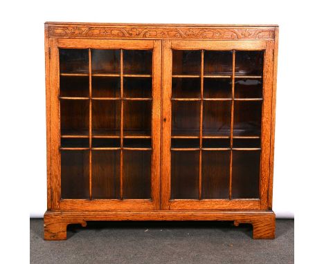 Light oak bookcase, two glazed panelled doors enclosign chelves, bracket feet, width 104cm, depth 28cm, height 100cm.