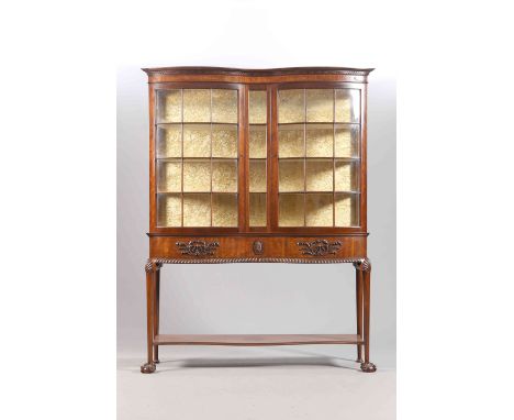 A MAHOGANY VITRINE IN IRISH CHIPPENDALE STYLE, LATE 19TH CENTURY, the serpentine front with a pair of doors over a frieze wit