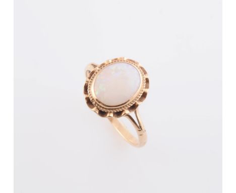 AN OPAL RING, the oval cut opal collet set to the centre of a delicate scalloped edge mount with subtle rope work detailing, 