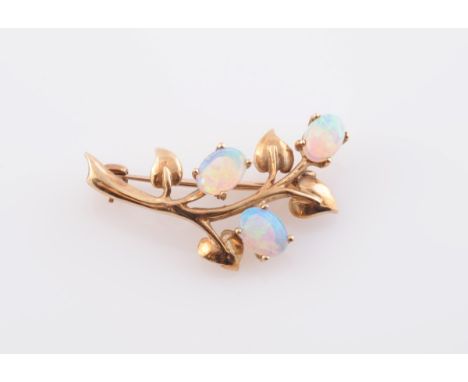 AN OPAL SET BROOCH, formed as a curving tree branch with four moulded metal leaf shaped mounts and three oval cabochon cut op