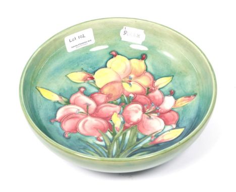 A Walter Moorcroft African Lily Pattern Bowl, on a green ground, impressed factory marks and blue painted monogram, 22cm diam