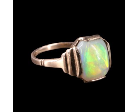 A faux opal dress ring comprising an oblong cabochon of approx 8 x 10 mm bezel-set between the terraced shoulders of a 9 ct y