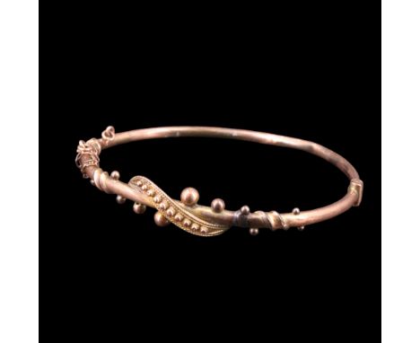 A late 19th / early 20th Century 9 ct rose gold hinged bangle faced with a scroll and pellets, 6 cm, 5.6 g 
