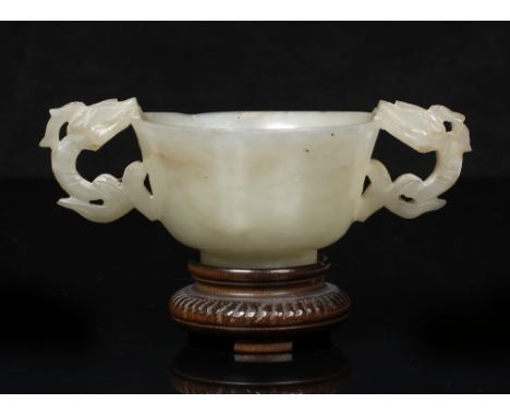 A Chinese mutton fat jade wine cup 19th Century the conical shaped bowl supporting pierced and carved chi-lin dragon handles 