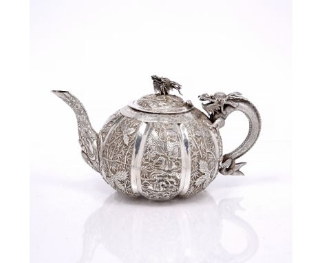 A Chinese export market white metal teapot late 19th Century with dragon finial and handle, the panelled sides alternating wi