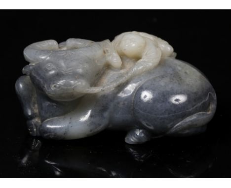 A Chinese carved dark grey and white mottled jade pebble 18th Century carved as a reclining water buffalo looking over left s