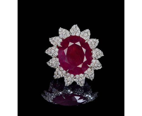 18k white gold ring, centred on a claw-set oval faceted ruby weighing approximately 15 ct, surrounded by diamonds weighing ap