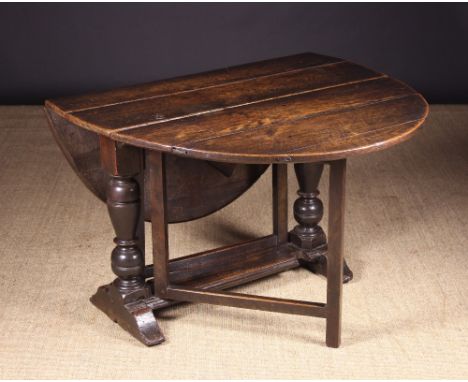 A 17th Century Oak Gate Leg Table.  The oval top on bold baluster & ball turned end supports with sledge feet united by a mou