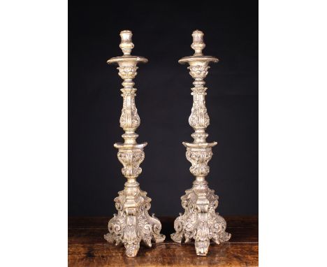 A Pair of Fine Early 18th Century Italian Silver-Giltwood Candlesticks, Circa 1700. The candle-cups raised on elaborately car